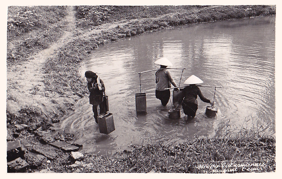 Des femmes transportent l'eau d'un étang à l'aide du Quang Ganh