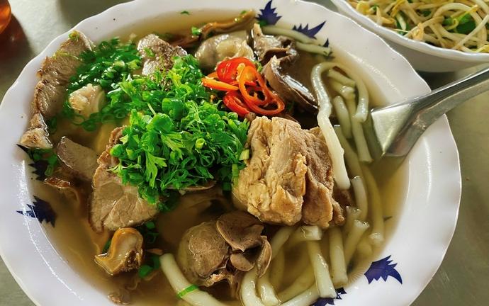Le b&aacute;nh canh Bến C&oacute;, une sp&eacute;cialit&eacute; de Tr&agrave; Vinh reconnaissable &agrave; ses grosses nouilles de riz, son bouillon clair et ses g&eacute;n&eacute;reuses garnitures de porc et d&rsquo;abats.
