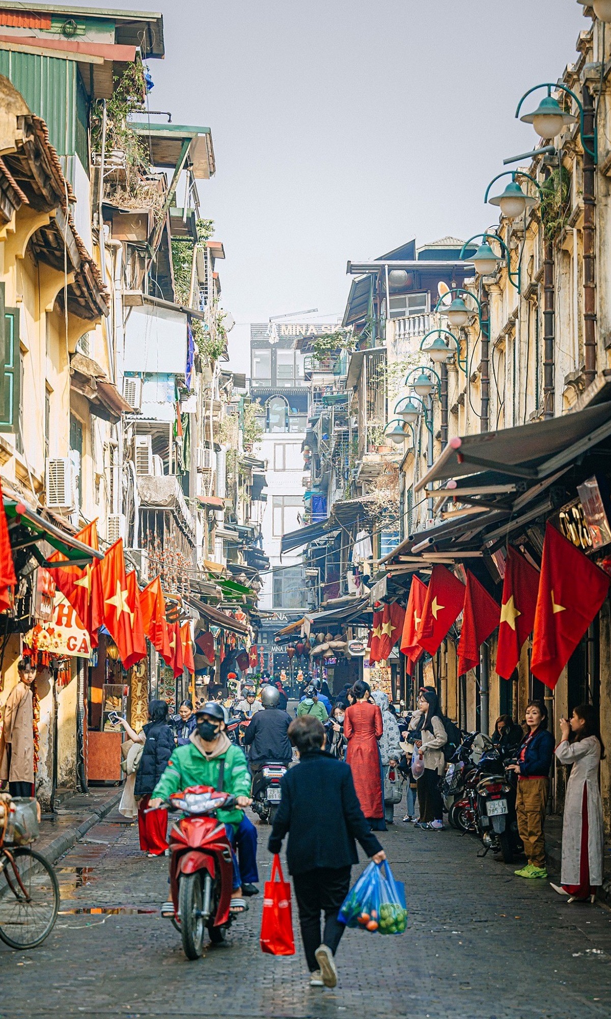 La rue Tạ Hiện s'illumine de rouge avec les drapeaux nationaux, attirant de nombreux jeunes en áo dài venus immortaliser l'esprit du Têt. Photo : Joakim Hall