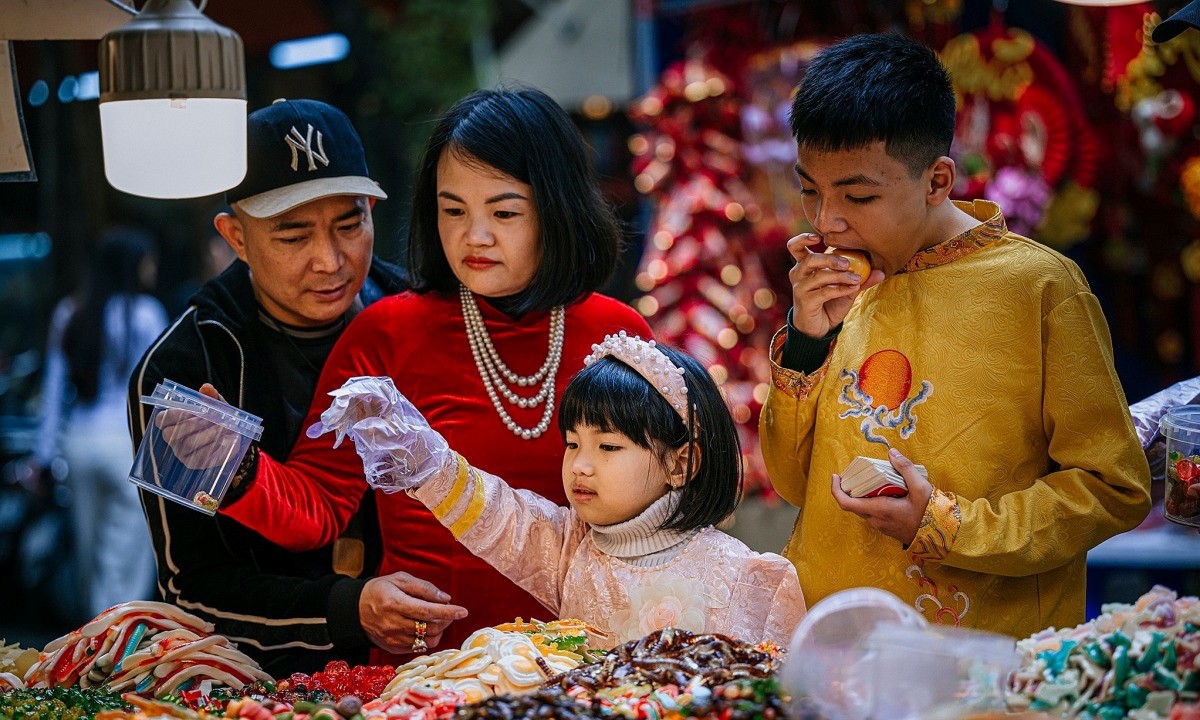 Une famille choisit ensemble des articles pour le Têt dans une échoppe de rue au cœur du Vieux Quartier. Photo : Joakim Hall