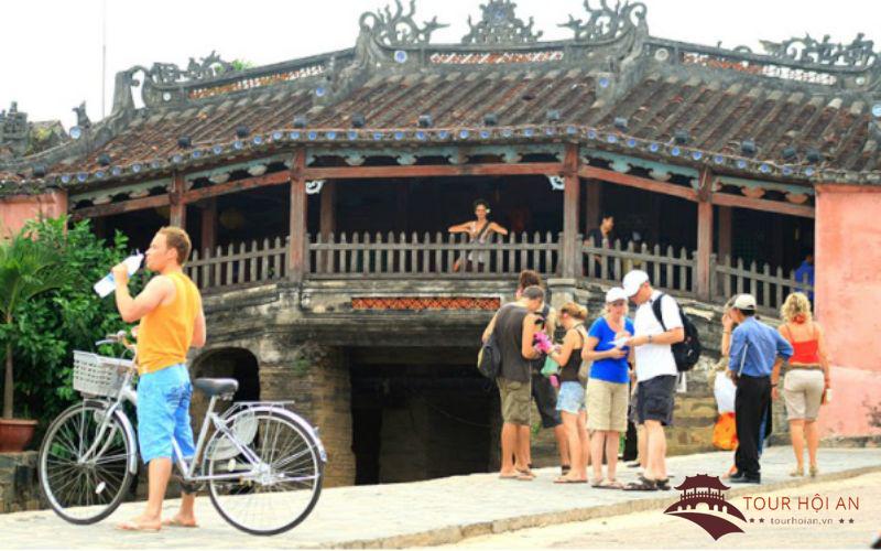 Les touristes font du vélo pour explorer le pont couvert japonais de Hoi An