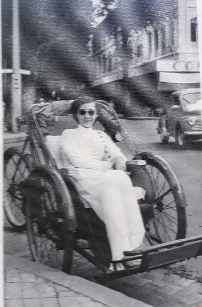 Une femme en áo dài pose dans un cyclo-pousse à Saigon dans les années 1930, symbole du charme colonial d’antan.