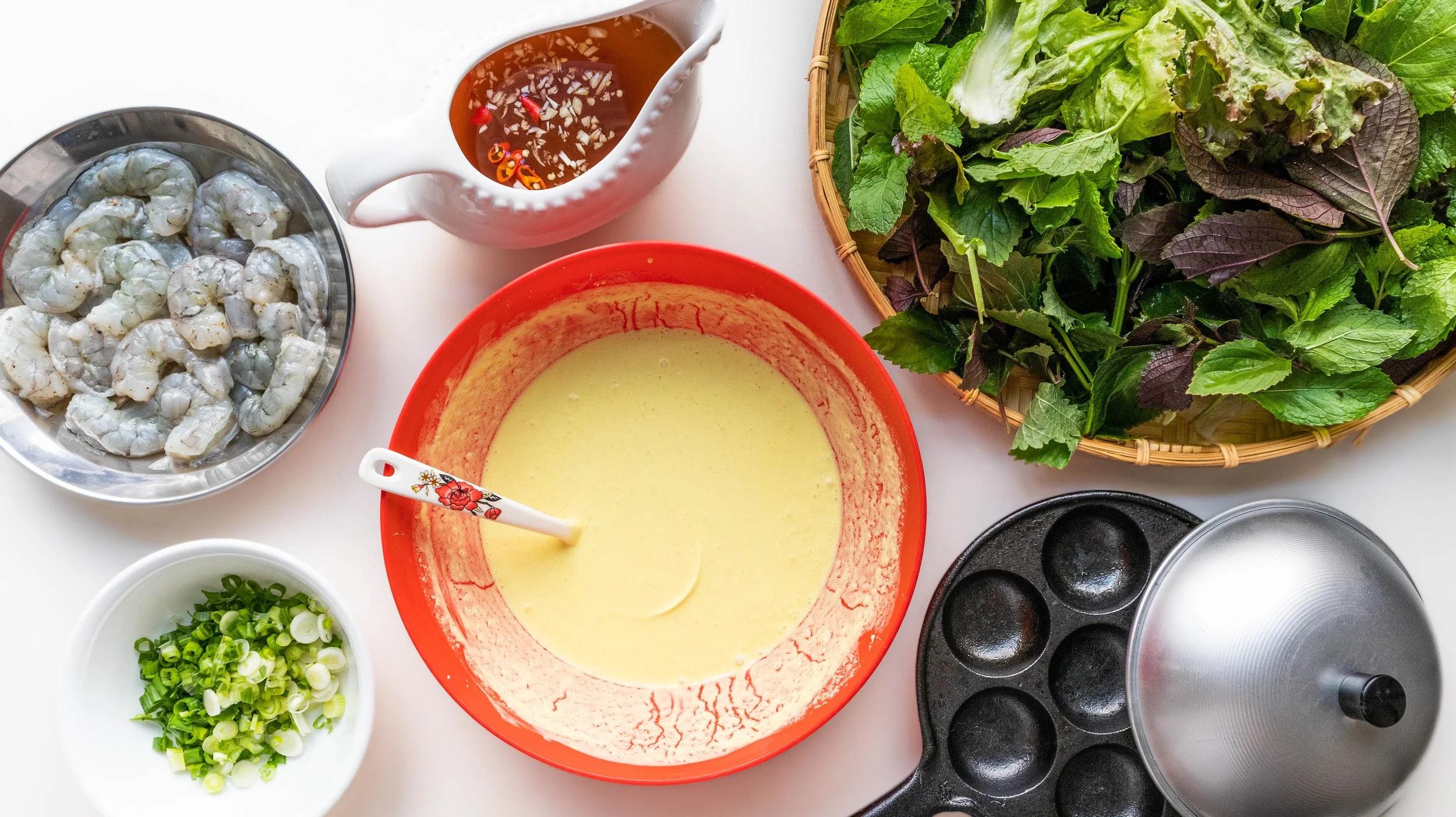 Les ingr&eacute;dients du b&aacute;nh khọt : farine de riz, crevettes fra&icirc;ches, oignons verts, lait de coco et herbes aromatiques, pour de petites bouch&eacute;es croustillantes aux saveurs du Sud du Vietnam...